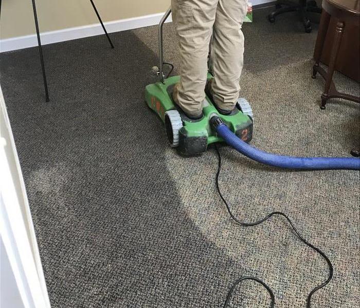 person extracting water from carpet in a room 